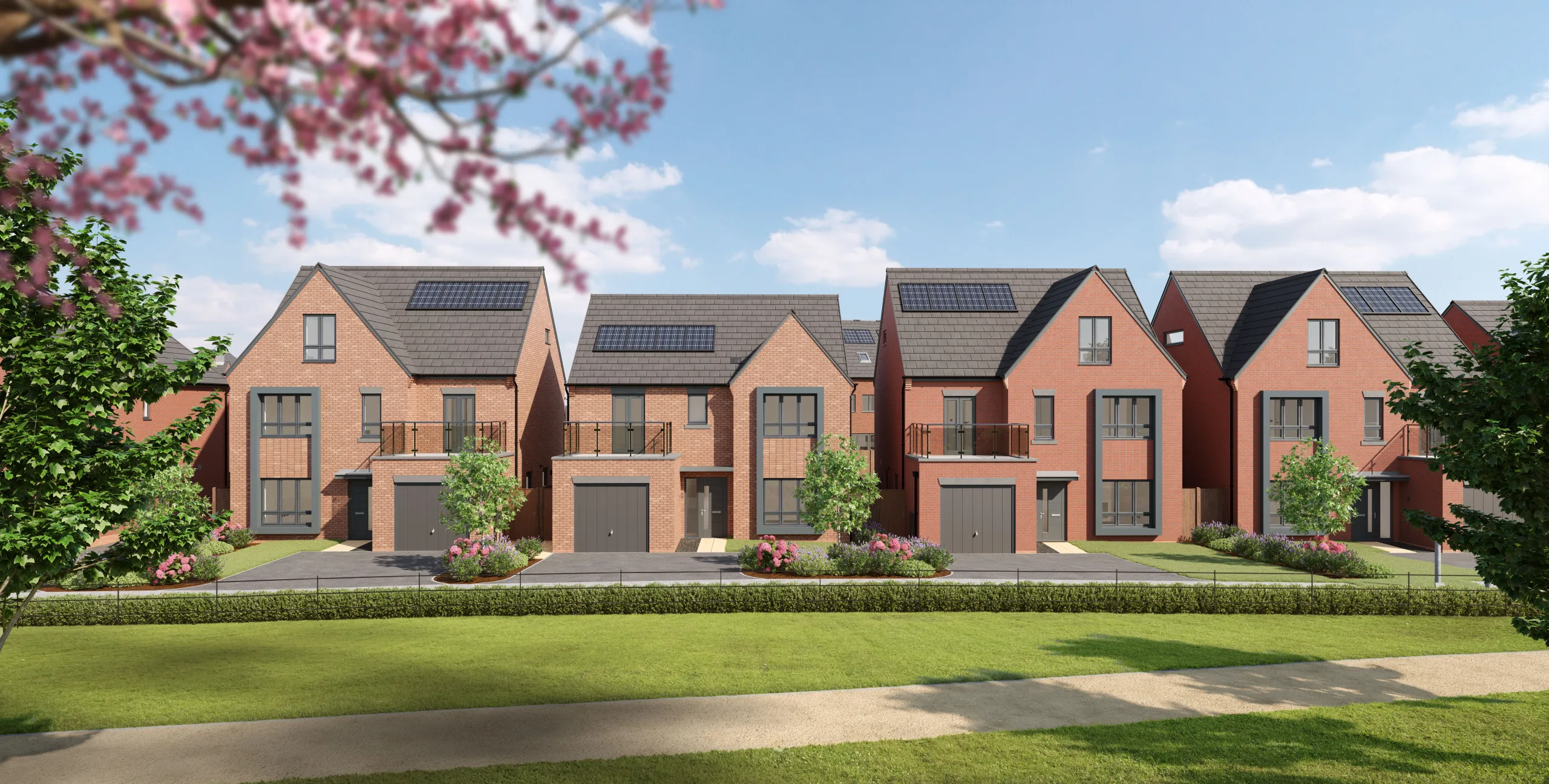 Four Anwyl Homes new build homes, each with a redbrick exterior and gabled roofs, are set amidst a neatly manicured lawn under a bright blue sky.