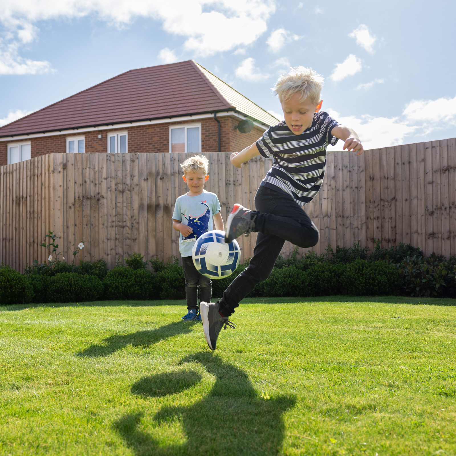 Two young boys playing football in the garden 