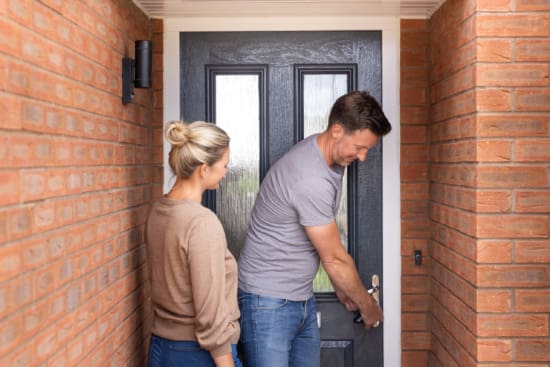 Excited Young Couple Opening Front Door Of New Home