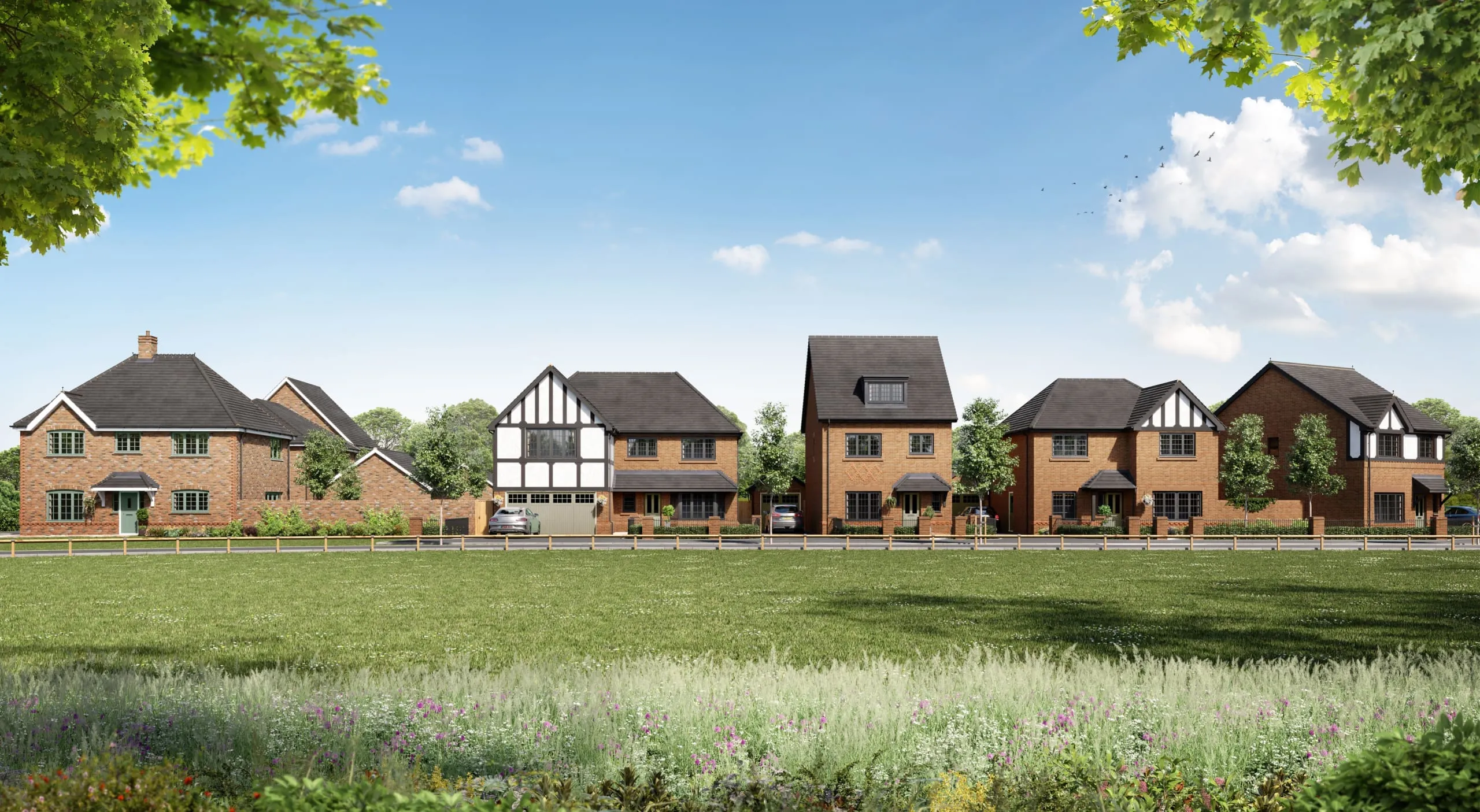 A row of detached, new build homes by Anwyl Homes, featuring red brick exteriors and gabled roofs, is set against a backdrop of trees and a lush, green lawn.
