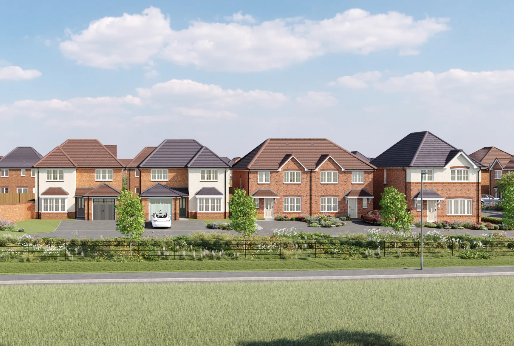 A row of Anwyl Homes new build homes features red brick exteriors with gabled roofs and green garages, set on neatly landscaped lawns with trees and a clear sky overhead.